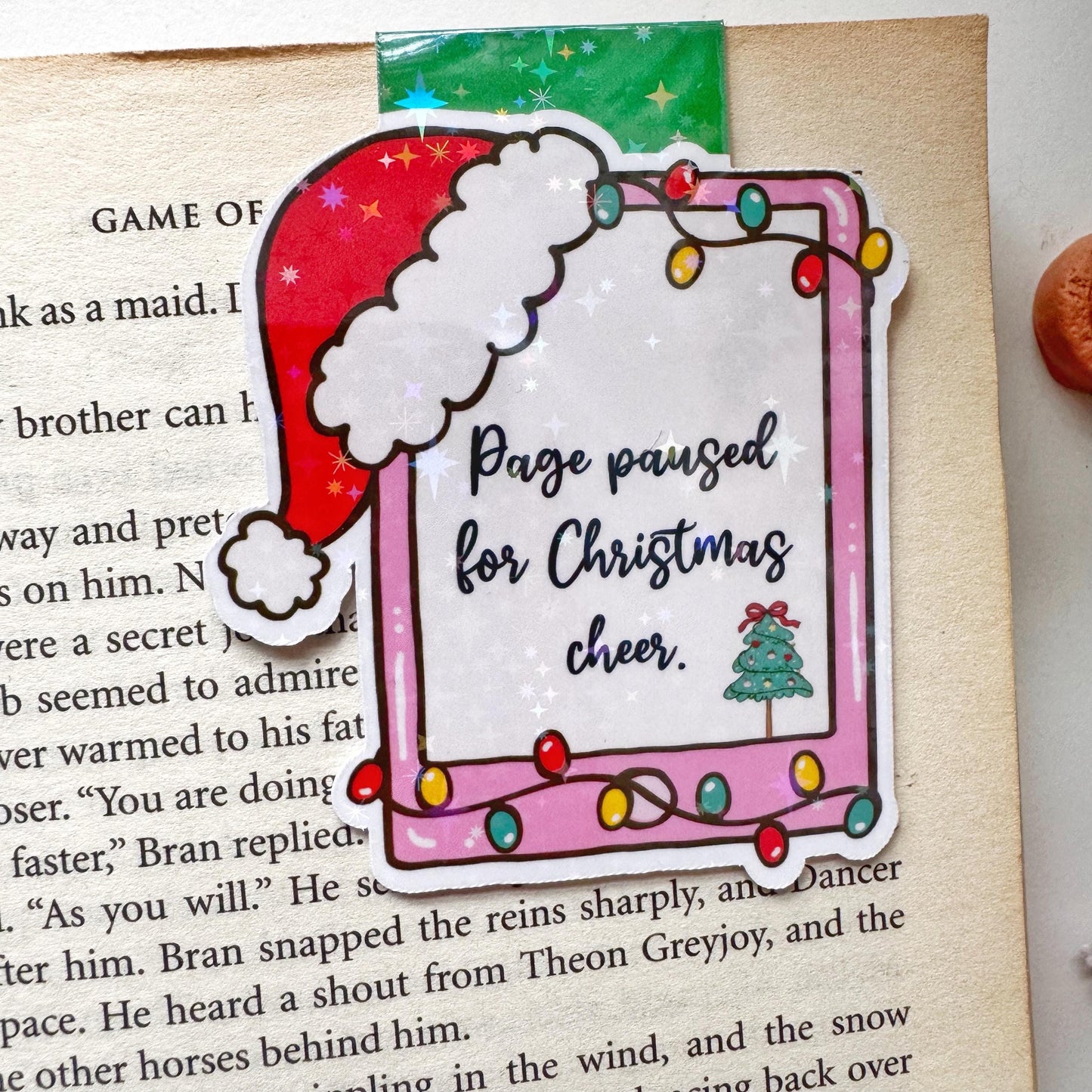 Page paused for Christmas Cheer Santa Cap Magnetic Bookmark: Book Lover Gift