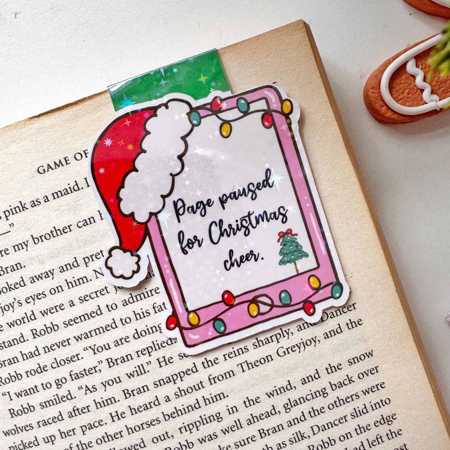 Page paused for Christmas Cheer Santa Cap Magnetic Bookmark: Book Lover Gift